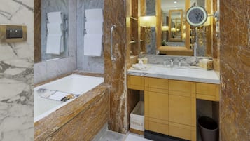 Un baño moderno con lavamanos de mármol, un espejo grande y un perchero para toallas.