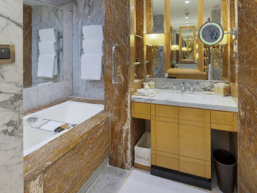 A modern bathroom with a marble sink, a large mirror, and a towel rack.