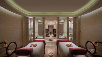 A spa room with two beds, a central seating area, and a mirror.