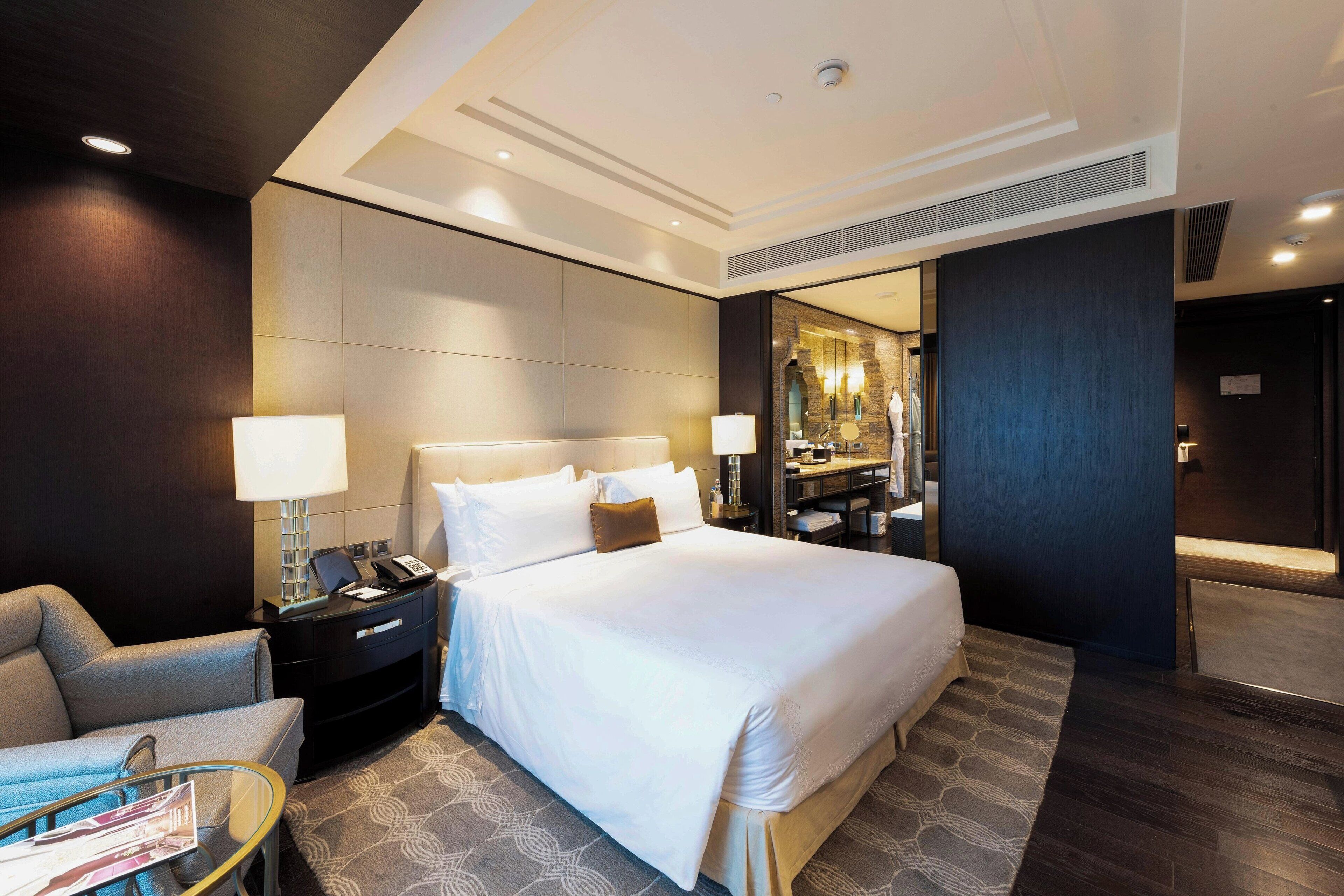 A hotel room with a large bed, bedside tables, a desk, and a mirror.