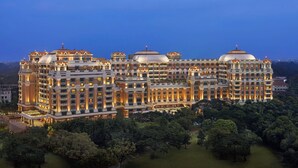 Un hotel grande de varios pisos con una fachada imponente, múltiples cúpulas y un jardín bien cuidado.