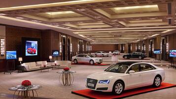 Amplio salón de ventas con varios autos expuestos, un área de descanso cómoda y un diseño de techo moderno.