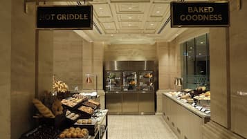 Zona de desayuno de hotel con letreros que dicen 'HOT GRIDDLE' y 'BAKED GOODNESS'.