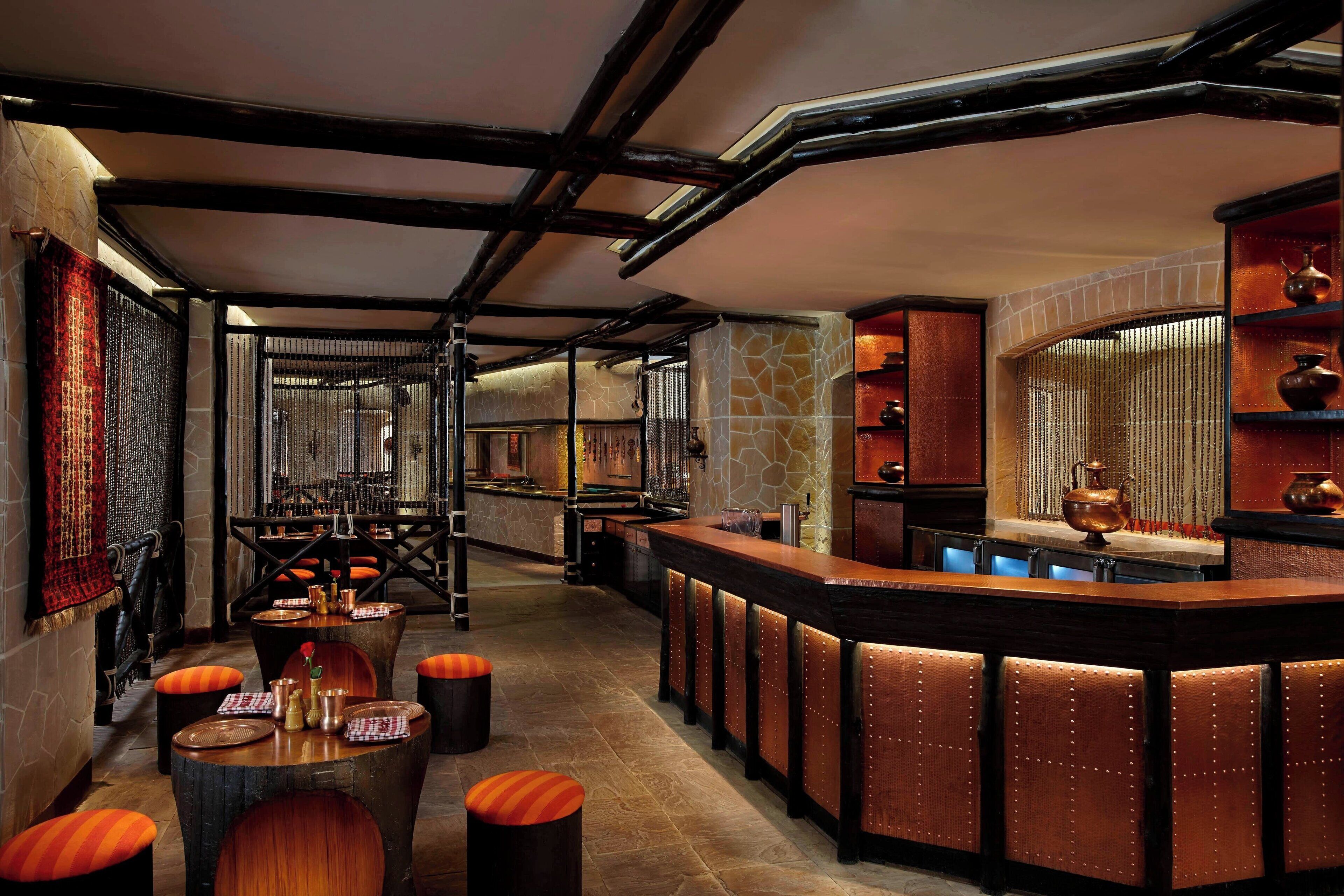 A bar area with a wooden counter, stools, and a stone wall.