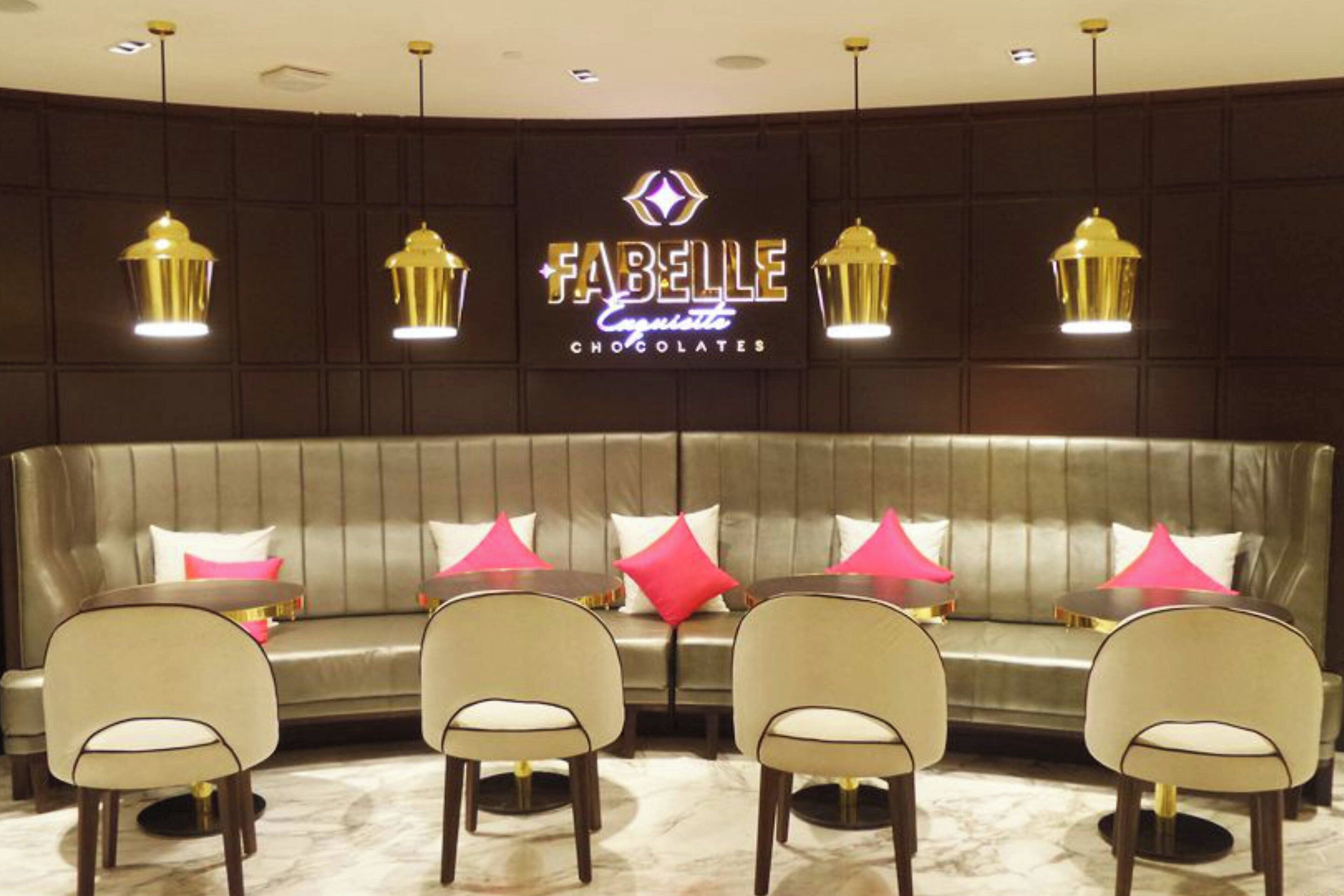 Un salón de FABELLE Chocolates con un sofá de cuero, cuatro sillas e iluminación colgante.