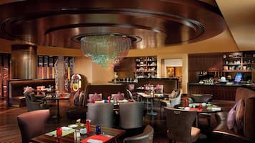 Un restaurante con una decoración moderna, que incluye un candelabro, muebles de madera y una zona de bar.