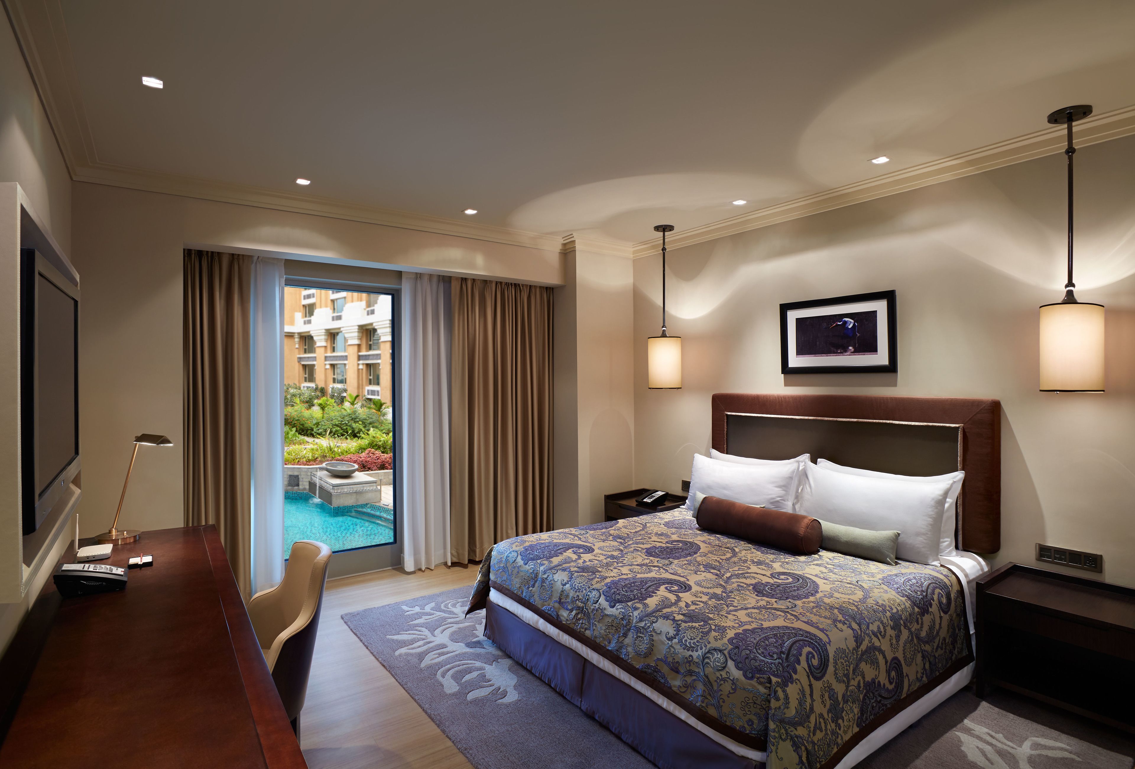Habitación de hotel con una cama grande, un escritorio, un televisor y vista a una piscina.