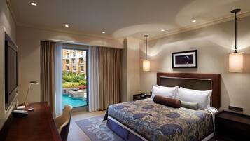 Habitación de hotel con una cama grande, un escritorio, un televisor y vista a una piscina.
