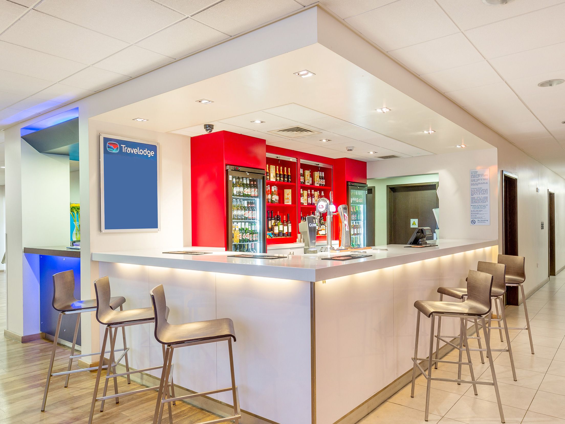 A modern reception area with a bar, seating, and a Travelodge sign.