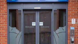 A hotel entrance with automatic doors, a 'Welcome' sign, and a 'No Smoking' sign.