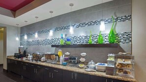 A modern kitchen with a granite countertop, built-in cabinets, and a backsplash with mosaic tiles. - La Quinta Inn & Suites by Wyndham Pearsall (Pearsall)