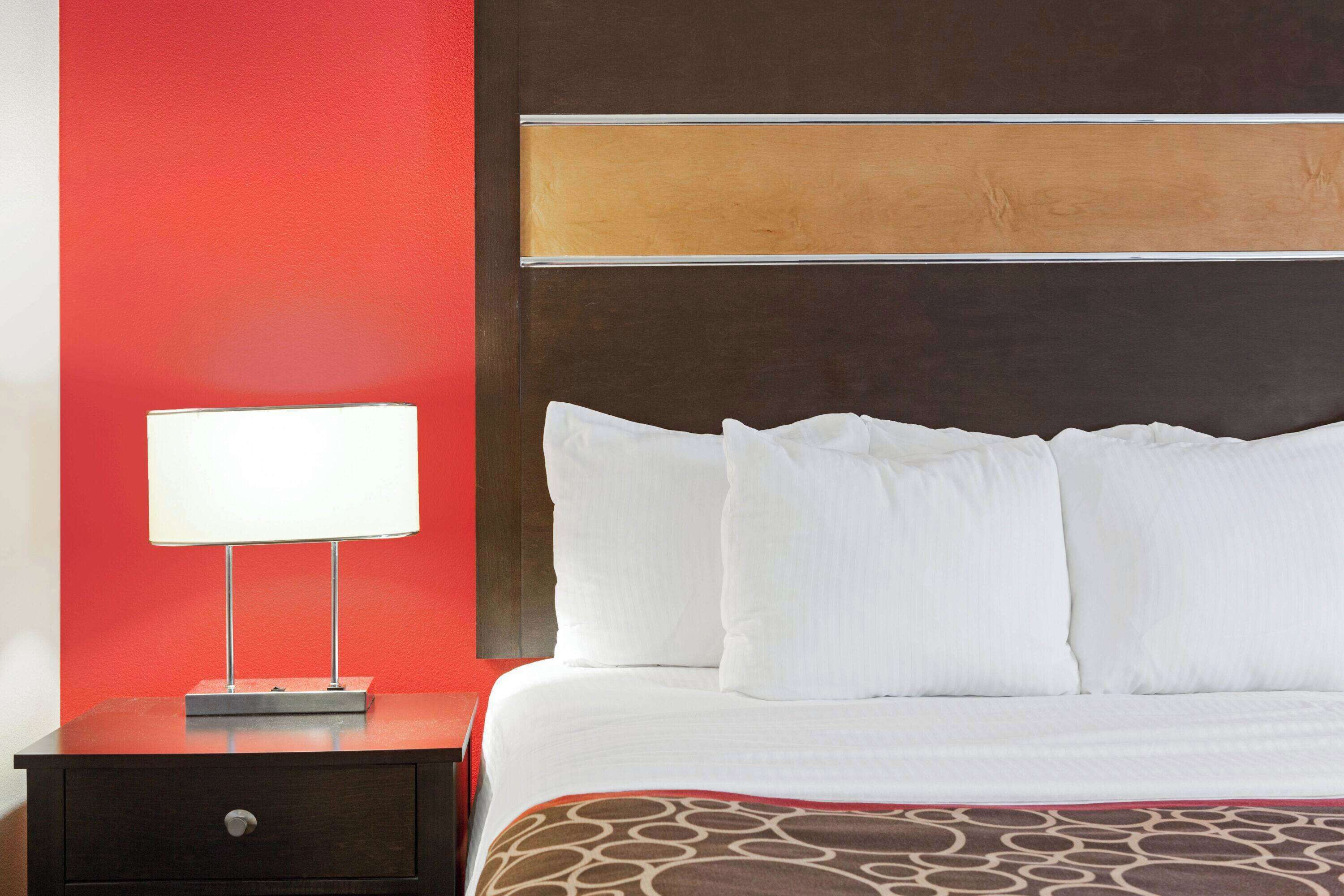 Una habitación de hotel con una cama, una mesita de noche y una lámpara.