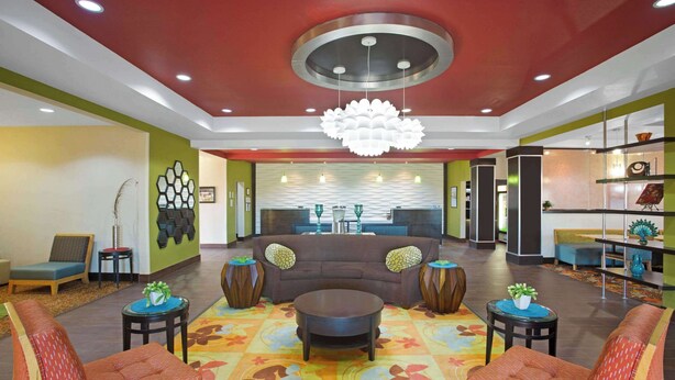 A lobby with a brown sofa, red patterned chairs, a central coffee table, and a colorful patterned rug. - La Quinta Inn & Suites by Wyndham Pearsall (Pearsall)