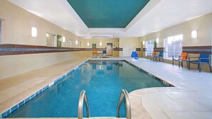 An indoor swimming pool with a tiled floor, a blue pool, and a ceiling with a green accent. - La Quinta Inn & Suites by Wyndham Pearsall (Pearsall)