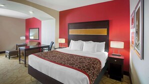 A hotel room with a large bed, a desk, a chair, and a nightstand with lamps. - La Quinta Inn & Suites by Wyndham Pearsall (Pearsall)