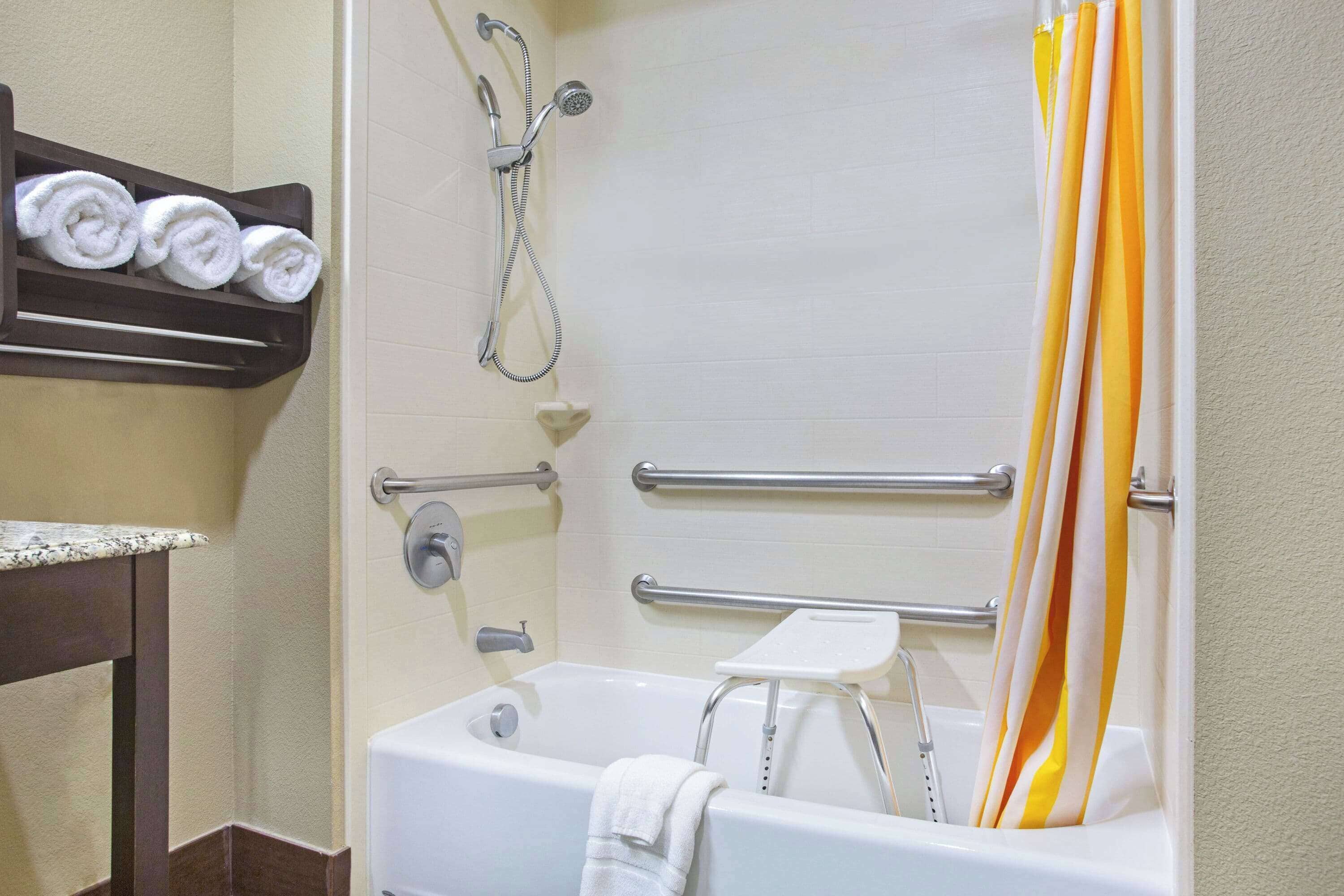 A bathroom with a bathtub, a shower, and a towel rack with towels.
