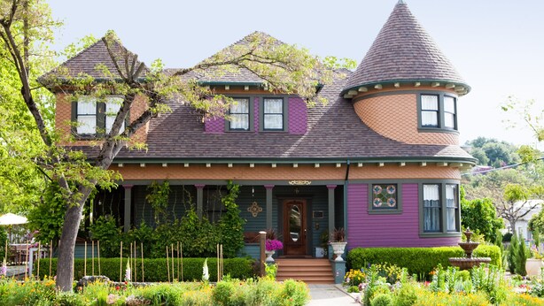 A Victorian-style house with a turret, a wrap-around porch, and a garden with various plants and flowers. - Kelley & Young Wine Garden Inn (Cloverdale)