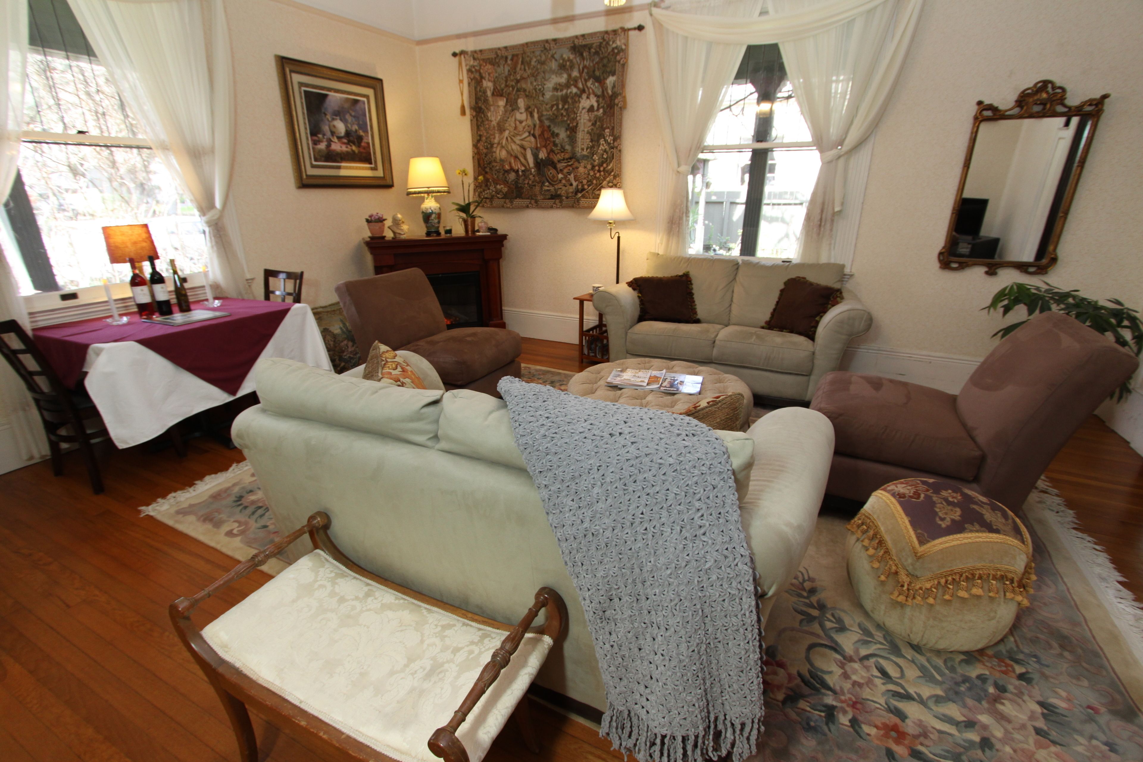 A cozy living room with a fireplace, a dining table with candles, and a large tapestry on the wall.