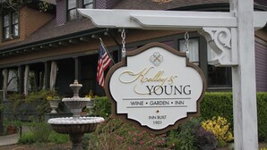 A sign for 'Kelley’s Young' with a garden fountain and an American flag. - Kelley & Young Wine Garden Inn (Cloverdale)