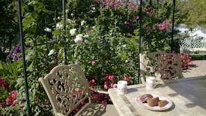 A garden patio with two ornate chairs, a table, and a plate of pastries. - Kelley & Young Wine Garden Inn (Cloverdale)