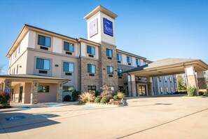 A multi-story hotel with a prominent sign on the tower, a covered entrance, and a parking area with handicapped-accessible spaces. - Sleep Inn & Suites Center (Center)