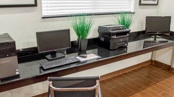 A reception desk with a computer, printer, keyboard, and a chair.