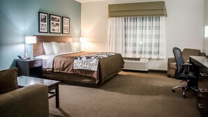 Ein Hotelzimmer mit Bett, Nachttischen, Schreibtisch, Stuhl und einem Fenster mit Vorhängen.