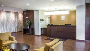 Ein Hotel-Empfangsbereich mit Empfangstresen, einer Couch, einem Couchtisch und einer Zimmerpflanze.