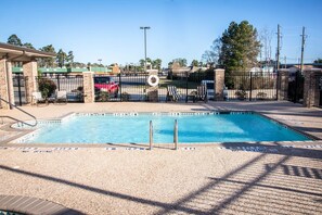 A rectangular pool with a no diving sign, surrounded by a fence and chairs.