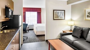Hotellihuone, jossa on pieni keittiö, sänky, sohva, työpöytä ja lamppu.