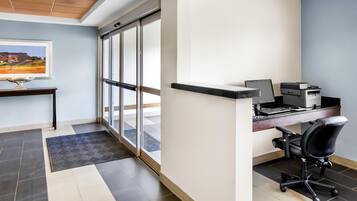 A modern office space with a desk, chair, printer, and a large window.