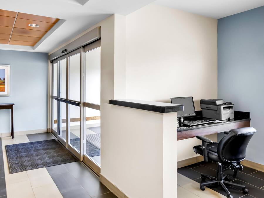 A modern office space with a desk, chair, printer, and a large window.