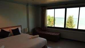 A hotel room with a large bed, a bench, and a window with a view of the sea. - Magic House Hostel (Cha-am)