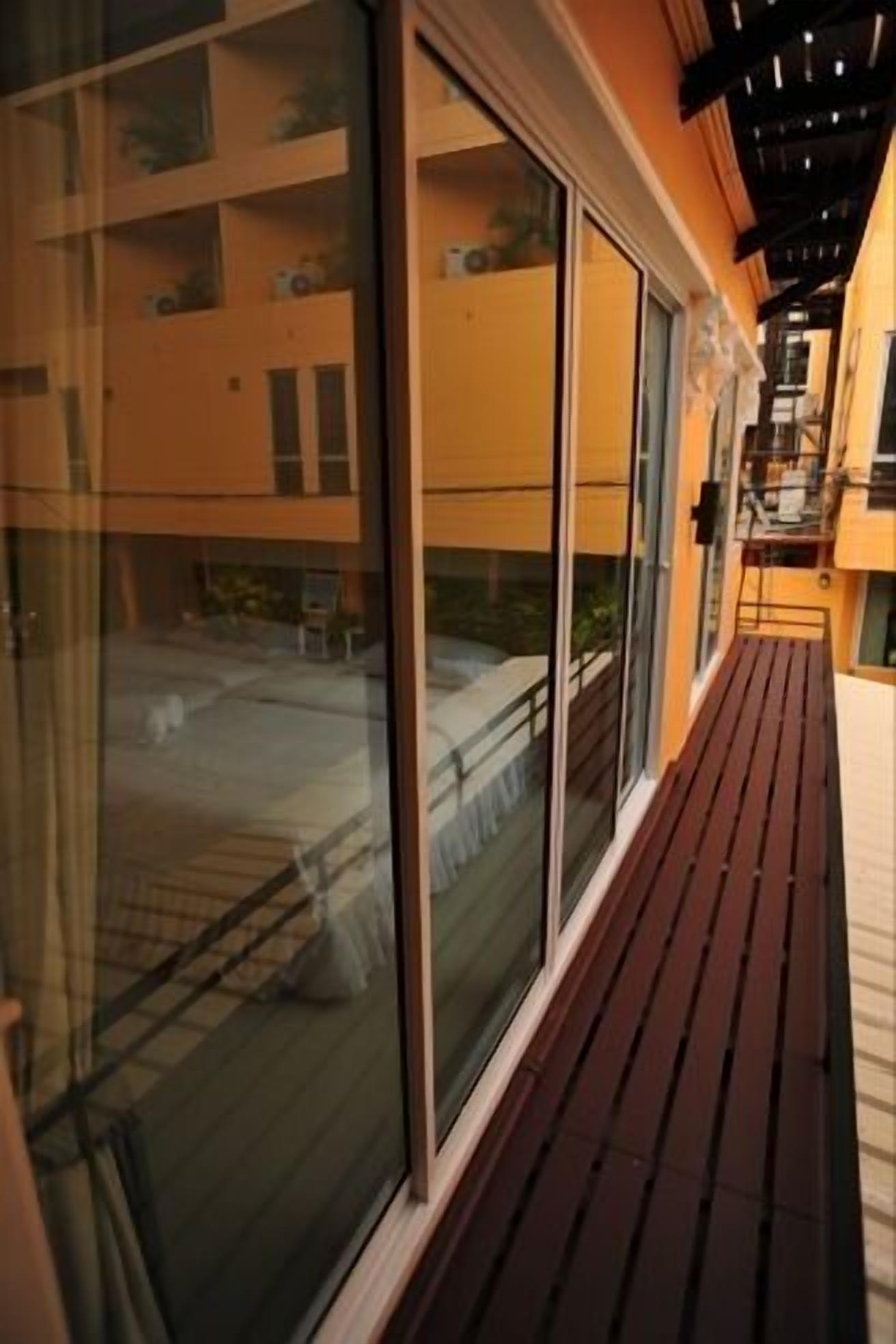 A balcony with a wooden floor and large sliding glass doors leading to an outdoor area.