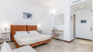 A bedroom with a bed, bedside tables, a desk, a chair, a mirror, and a wall-mounted air conditioner.