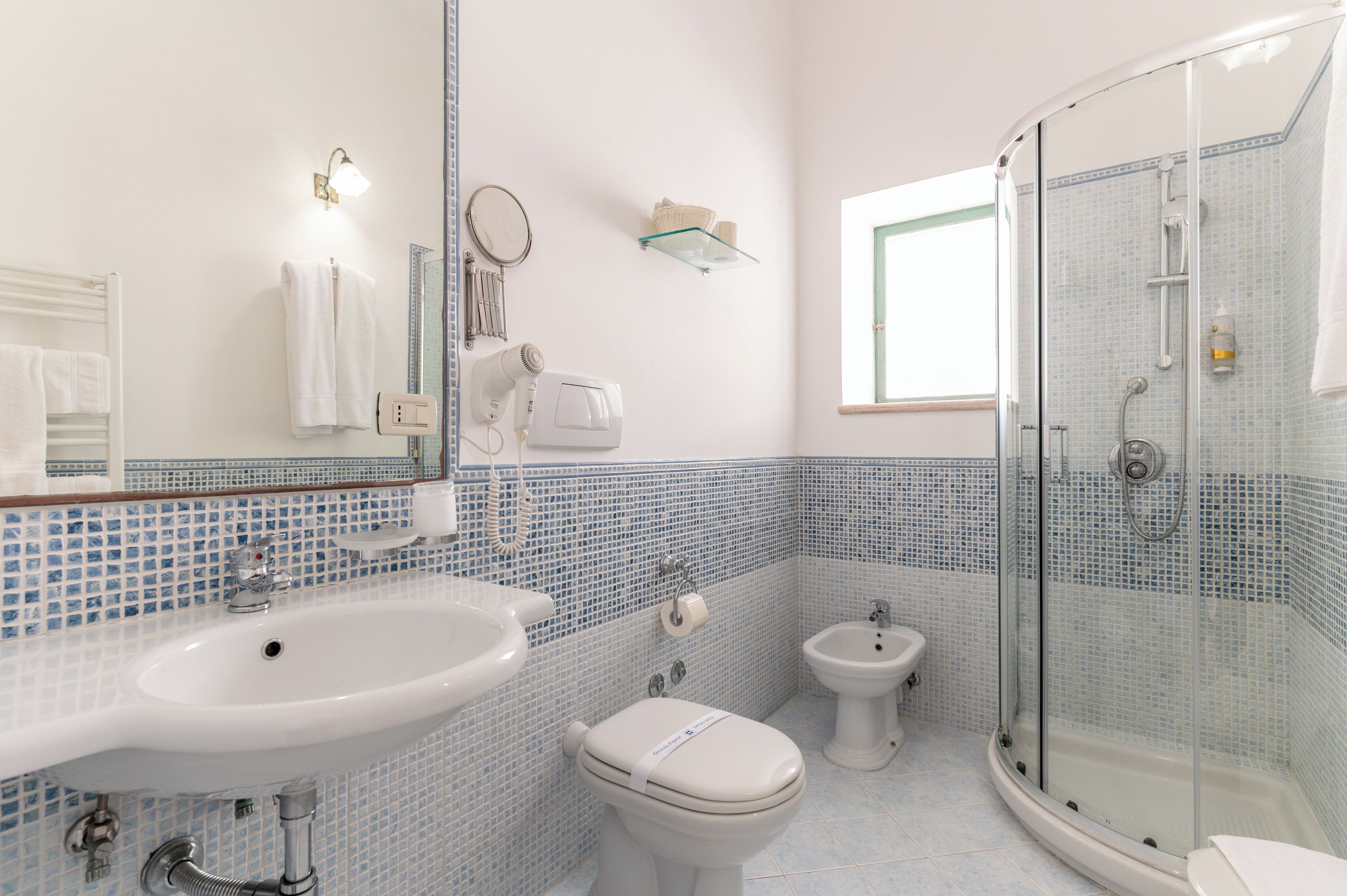 Ein Badezimmer mit Waschbecken, Toilette, Bidet und einer Duschkabine.