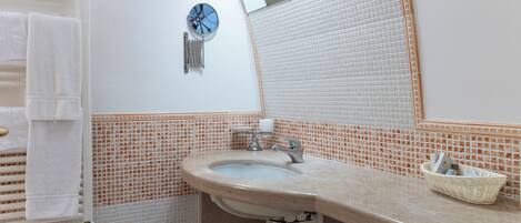 A bathroom with a sink, mirror, towel rack, and a small basket on the countertop.