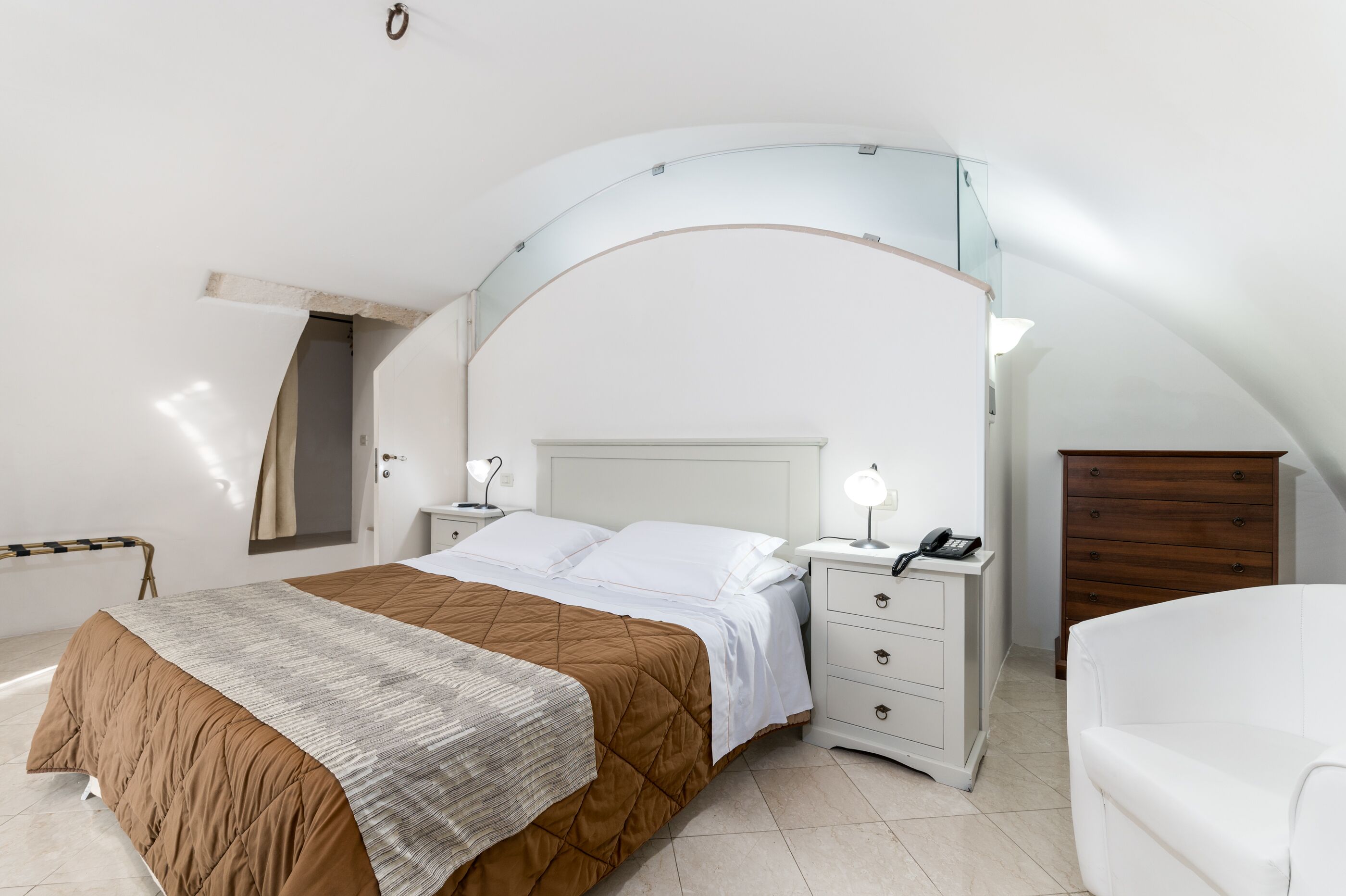 A bedroom with a bed, bedside tables, a nightstand, a dresser, and a chair.