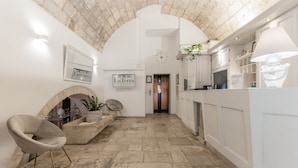 A spacious hallway with a stone ceiling, a fireplace, and a modern seating area. - Hotel La Terra (Ostuni)
