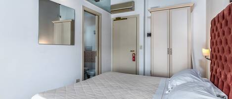 Un dormitorio con cama, armario, espejo y techo con vigas a la vista.