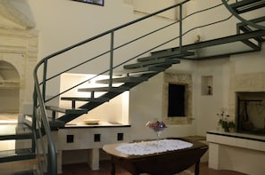 Stunning staircase leads to an upper level, featuring a kitchen area with a countertop and a bowl, alongside a fireplace.
