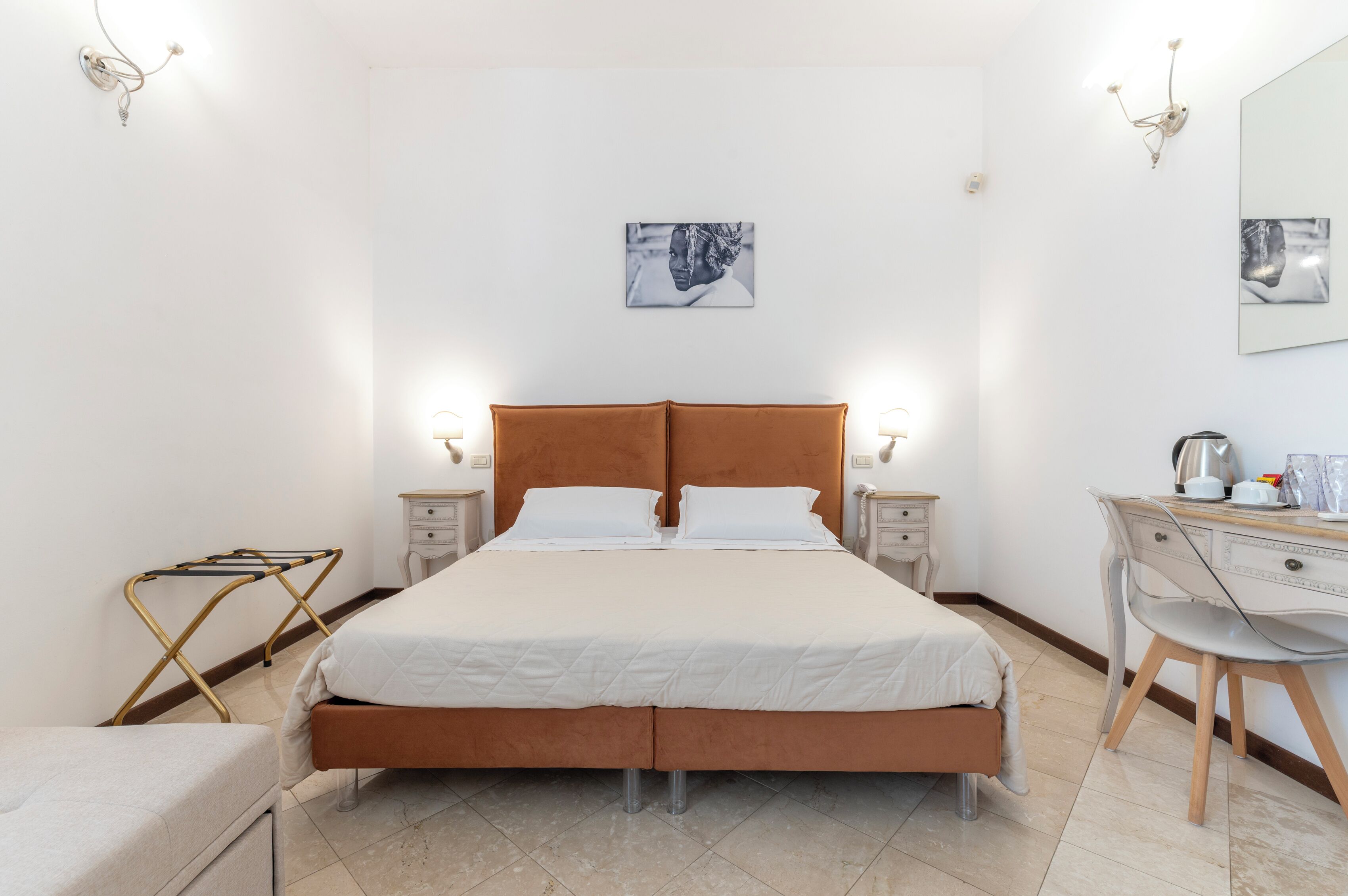 A neatly arranged bedroom with a large bed, bedside tables, a desk, and a chair.