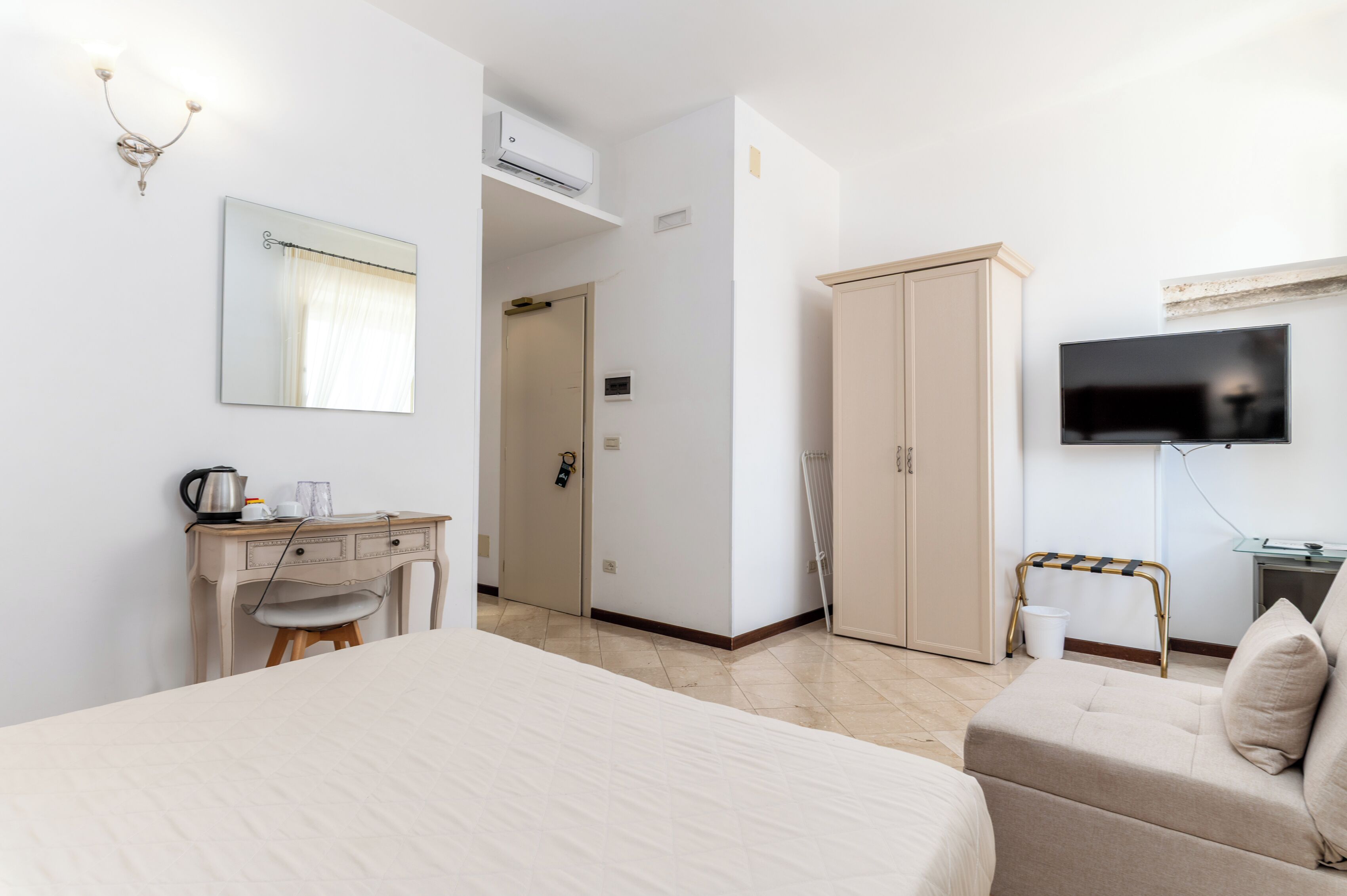 Hotelkamer met een bed, een bureau met stoel, een kledingkast, een televisie en een radiator.