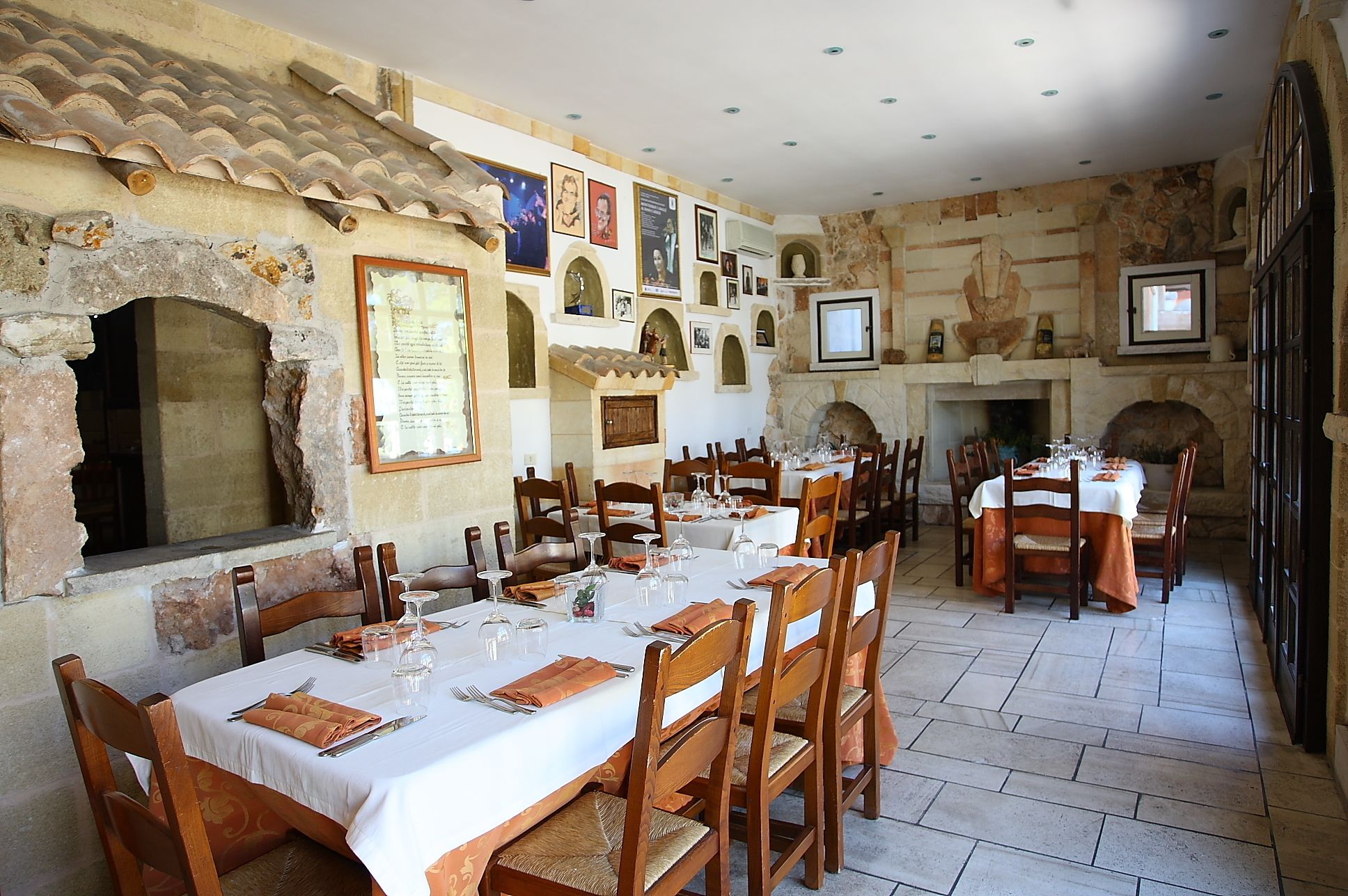 A restaurant with stone walls, wooden tables, and chairs.
