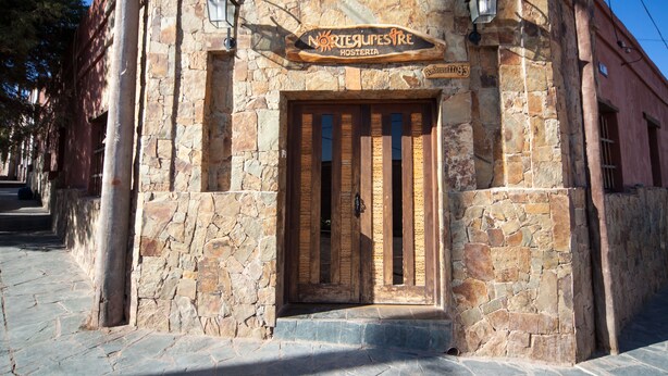 Un edificio de piedra con una puerta de madera y un letrero que dice "Nortesupes Hosteria".