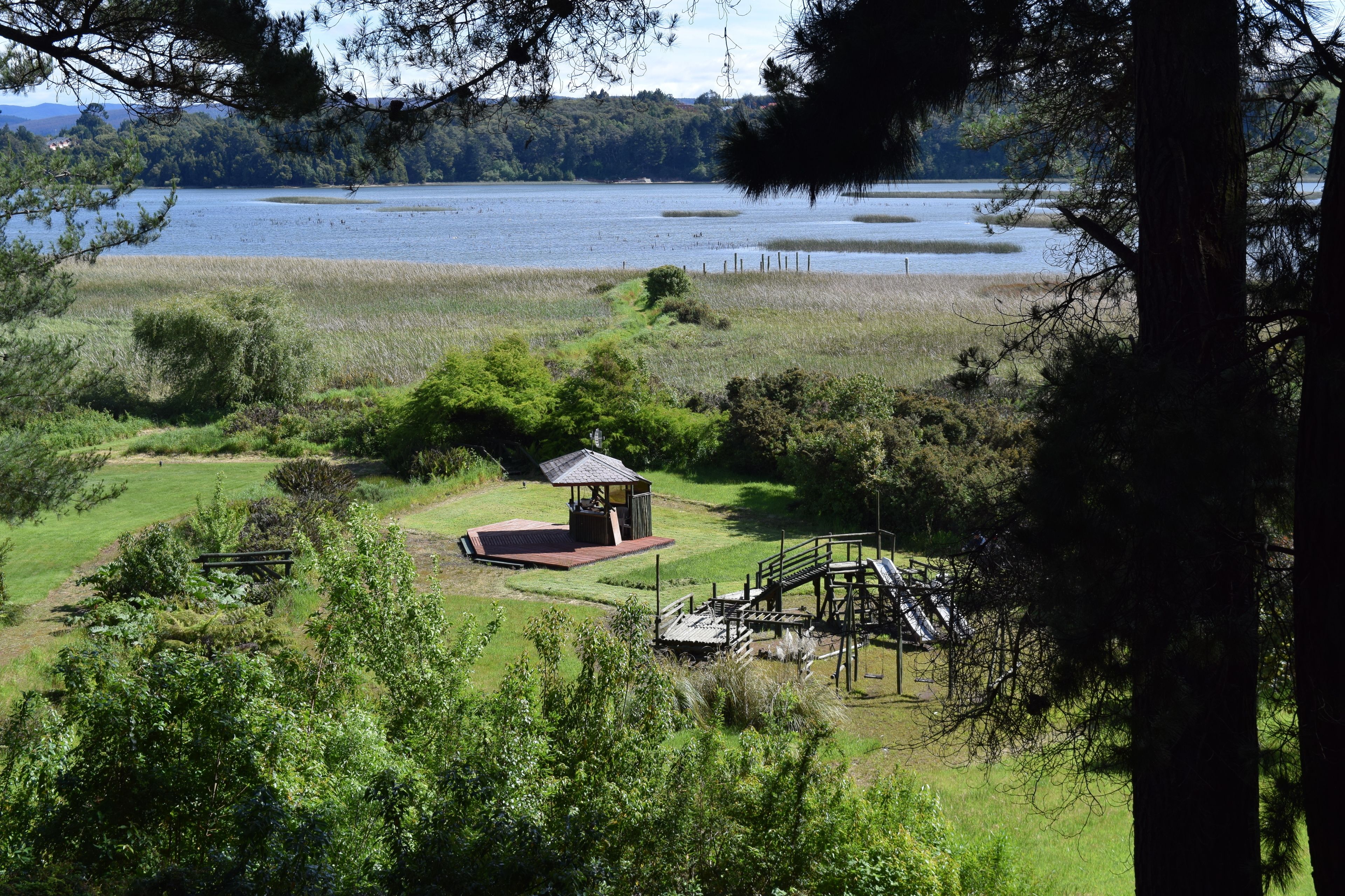 Un pavelló d'estiu al parc, amb un llac al fons.
