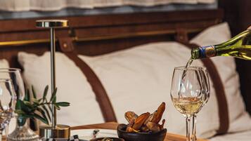 A dining table with a bottle of wine being poured into a glass, a bowl of food, and various dishes and utensils.