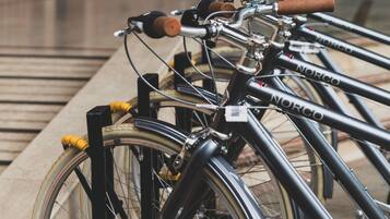 A row of bicycles parked in a covered area with a brick building in the background.