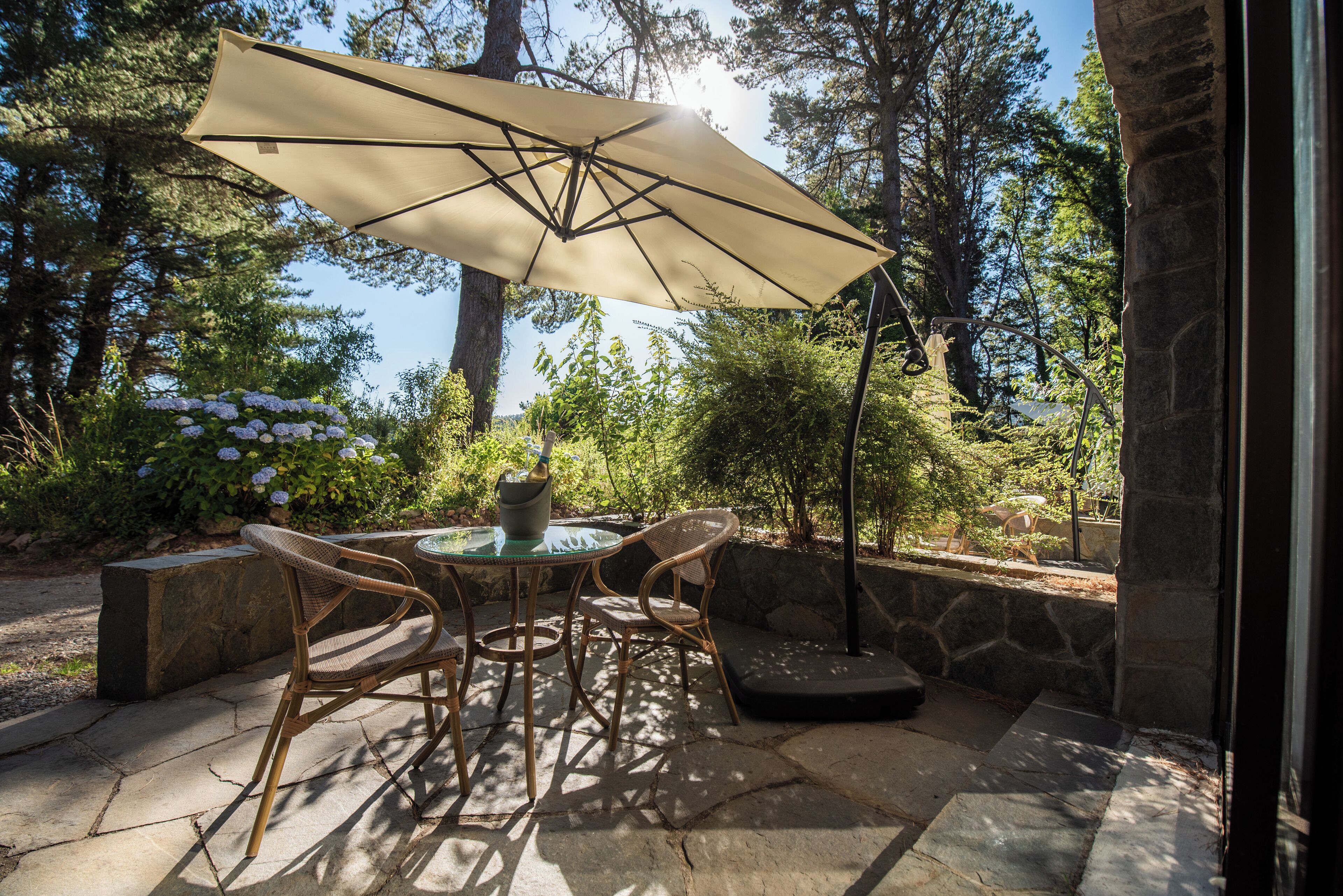 An outdoor patio with a round table, two wicker chairs, and a large umbrella.
