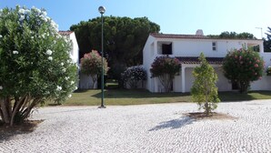 A courtyard with cobblestone flooring, surrounded by white buildings with red-tiled roofs and flowering plants. - Aldeia da Falésia (Albufeira)